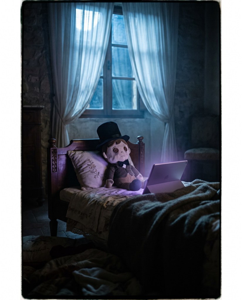 Un peluche con il cilindro sul cuscino, accanto a un tablet acceso