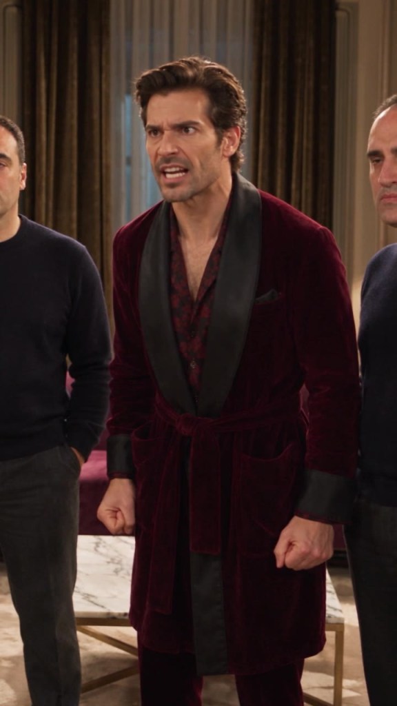 Carlo in vestaglia bordeaux urla in salotto, alle sue spalle Burbero vestito di nero